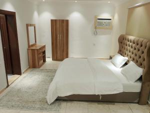 a bedroom with a large white bed and a wooden cabinet at شقق القنفذة بلس in Al Qunfudhah