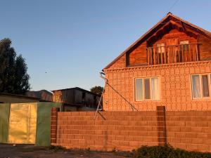 a house with a brick wall next to a fence at Sunrise Panorama in Bokonbayevo +20 photos