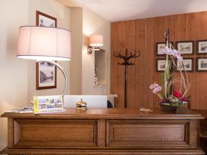 uma secretária num quarto com um candeeiro e flores em Logis Auberge du Valburgeois em Sainte-Gauburge-Sainte-Colombe