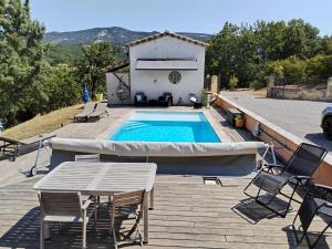 a swimming pool on a deck with a table and chairs at Le Cigalou - Drôme Provencale in Sainte-Jalle