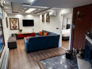 a living room with a blue couch and a tv at Mavi OTEL BOUTİQUE RESTAURANT in Mahmutlu