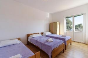 two beds in a room with a window at Apartman Viola 1 in Ugljan