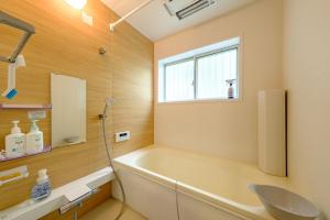 a bathroom with a tub and a sink and a window at Hale Kai Akiya in Yokosuka