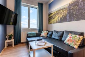 a living room with a black couch and a tv at Apartamenty Zieleniec in Duszniki Zdrój