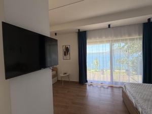 a bedroom with a flat screen tv and a large window at Sebi's Chalet with Sea View in Vlorë