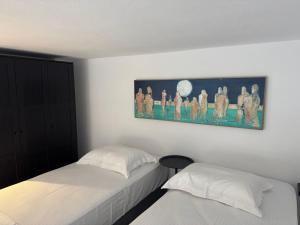 a bedroom with two beds and a painting on the wall at Cosy Stay in Platamonas