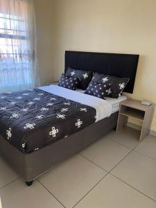 a bed with a black and white comforter and a table at Just Bed & bath by mama R in Newcastle