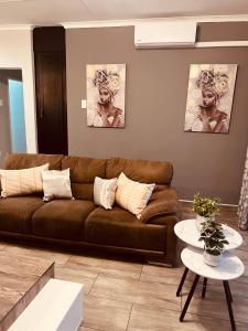 a living room with a brown couch and a table at Just Bed & bath by mama R in Newcastle