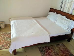 a bed with white sheets and pillows on it at Chris Hotel in Runda