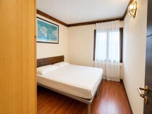 a small bedroom with a bed and a window at Hostdomus - B2-01 in Grange Sises