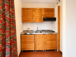 a small kitchen with wooden cabinets and a sink at Hostdomus - B2-01 in Grange Sises