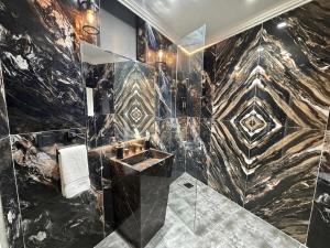 a bathroom with a black and gold marble wall at Regency Suite Hotel in Lahore