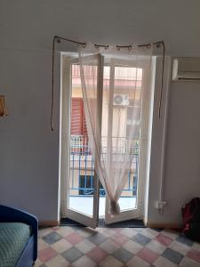 a door to a balcony with a window with curtains at Na' zà Ciccina in Palermo