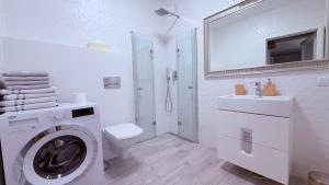 a white bathroom with a washing machine and a sink at Azymut in Darłowo