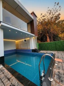 a swimming pool in front of a house at Parudeesa Pool Resort in Vattavada