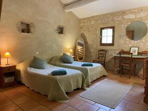 a bedroom with two beds and a table and chairs at La Ferme Terre Bio Provence in Lapalud