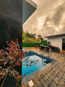 a swimming pool with a motorcycle parked in a yard at Parudeesa Pool Resort in Vattavada +10 photos