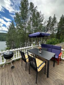 a wooden deck with a table and chairs and an umbrella at hytte ved innsjø in Skien