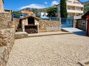 a stone building with a stone wall and a building at Holiday home Moni in Karlobag