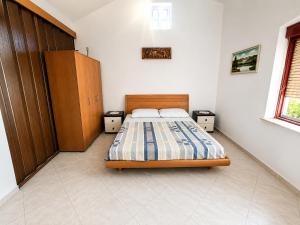a bedroom with a bed and a wooden cabinet at Holiday home Moni in Karlobag
