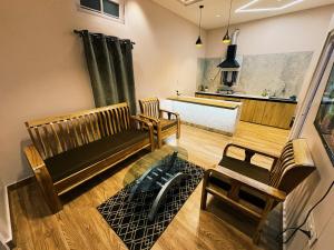 a living room with two wooden chairs and a kitchen at Arkan Villa in Guwahati