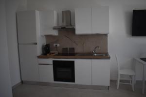 a kitchen with white cabinets and a sink and a refrigerator at Terrazza sul Borgo in Polignano a Mare