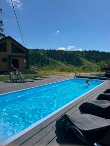 a swimming pool with lounge chairs on a wooden deck at Drin-lux-cotteges in Slavske