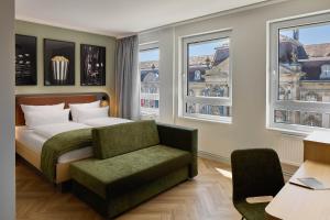 a bedroom with a bed and a chair and windows at Cinema City Hotel Europaplatz Karlsruhe - Brand New Boutique Hotel 2025 - in Karlsruhe