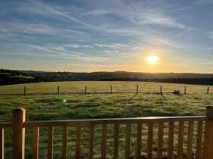 a view of a field with a fence and the sun at Arcadia Shepherds Hut in Ashwater