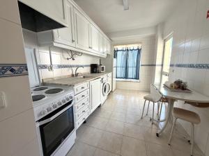 a kitchen with white cabinets and a sink and a table at Casa Canoa B in Armação de Pêra