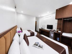 a hotel room with two beds and a television at Ho Sen Xanh Hotel in Hanoi +3 photos
