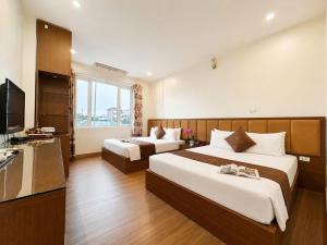 a hotel room with two beds and a television at Ho Sen Xanh Hotel in Hanoi