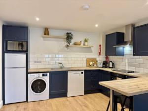a kitchen with blue cabinets and a washer and dryer at Apartment 299 - Clifden in Clifden