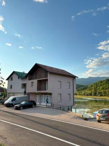 a building with cars parked on the side of a road at S&R Lake View Hostel in Konjic