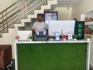 a man standing behind a green counter with acomputer at Keshav Vatika Palace - 800 meter Ram Mandir in Ayodhya