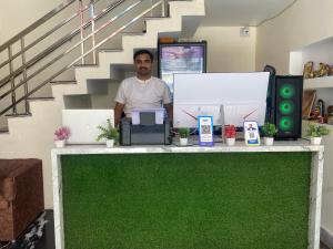 a man standing behind a counter with a green floor at Keshav Vatika Palace - 800 meter Ram Mandir in Ayodhya