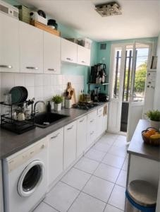 a kitchen with white cabinets and a washer at ANGLET, Chambre privée, QUARTIER CENTRAL in Anglet