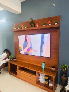 a flat screen tv sitting on top of a wooden entertainment center at Sofra service apartment by LUXE with swinging pool in Mysore