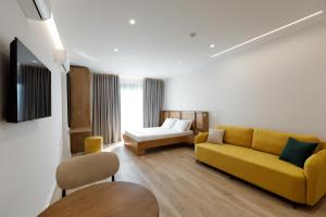 a living room with a yellow couch and a bed at Oleva Sea View Suites in Sarandë
