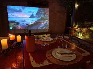 ein Holztisch mit Tellern und Weingläsern und ein Fernseher in der Unterkunft Krasberry in Komen