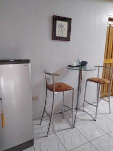 a kitchen with a table and two chairs and a refrigerator at Dream Garden Hotel in Solano