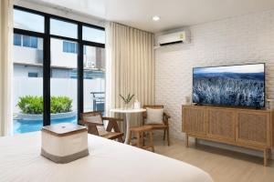 a bedroom with a bed and a tv on a wall at Beachfront Pool Access Apartment FREE Disney Plus in Bangsaen