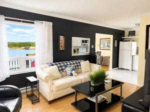 a living room with a white couch and a large window at The Wild Rose Cottage & Bird's Nest in Twillingate