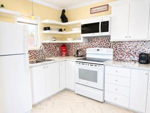 a white kitchen with white cabinets and appliances at The Wild Rose Cottage & Bird's Nest in Twillingate