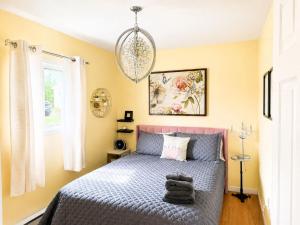 a bedroom with a bed and a chandelier at The Wild Rose Cottage & Bird's Nest in Twillingate +9 photos