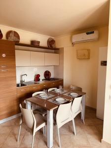 a kitchen with a wooden table and white chairs at Tropisal Apartamento in Santa Maria