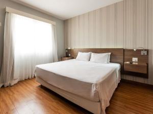 a bedroom with a large bed and a large window at Ibis Styles Campinas Alphaville in Campinas