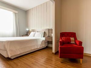 a bedroom with a bed and a red chair at Ibis Styles Campinas Alphaville in Campinas +128 photos