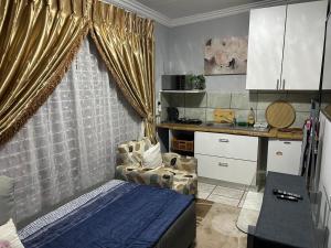 a bedroom with a bed and a chair and a kitchen at The Family Room in Krugersdorp