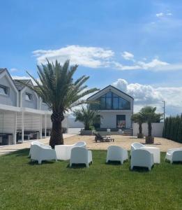 a group of white chairs on the grass in front of a building at Silver Park Resort 10m do plaży in Gąski